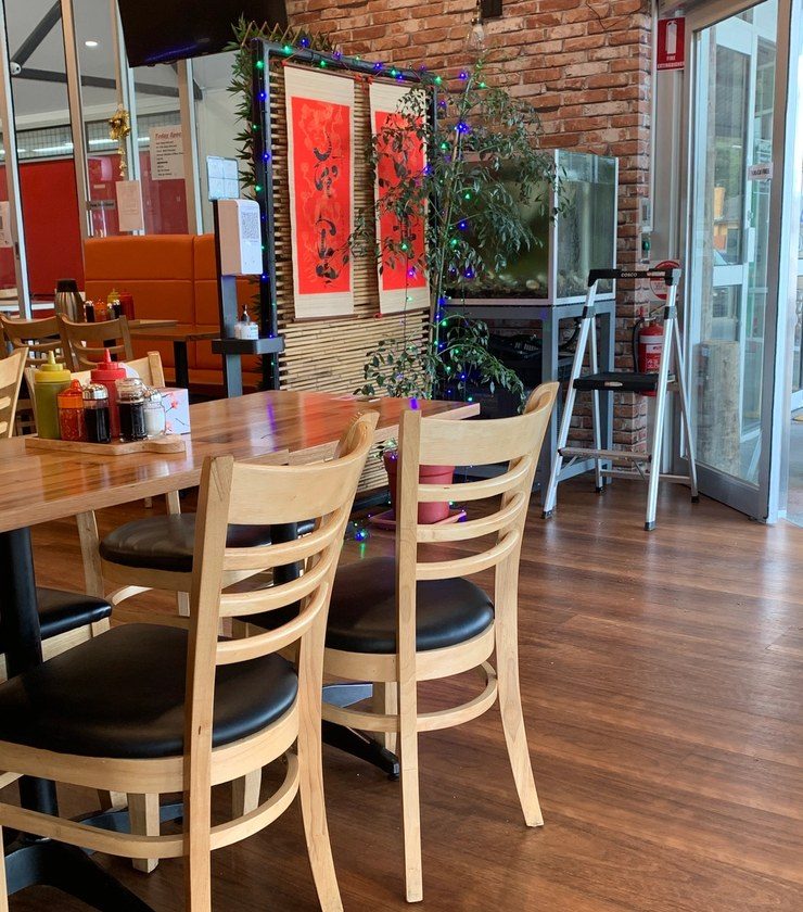 The Cô Năm dining room set for service, timber tables and plants