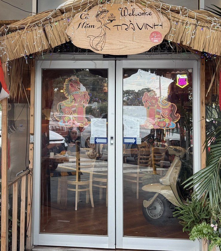 The Athol Road entrance under a thatched awning, with a red lantern and the carved Cô Năm Trà Vinh sign