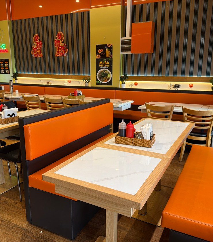 Orange booths and marble-top tables under a VIP Lounge neon sign at Windsor Avenue