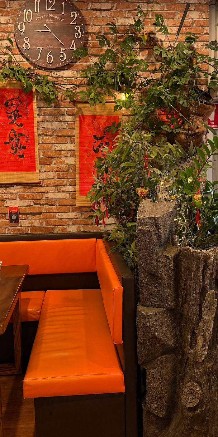 Inside Cô Năm on Athol Road: warm timber room, orange booths, plants and neon