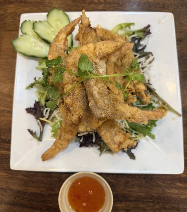 Salt and pepper soft shell crab on a bed of leaves with sliced cucumber, and a small dish of dipping sauce