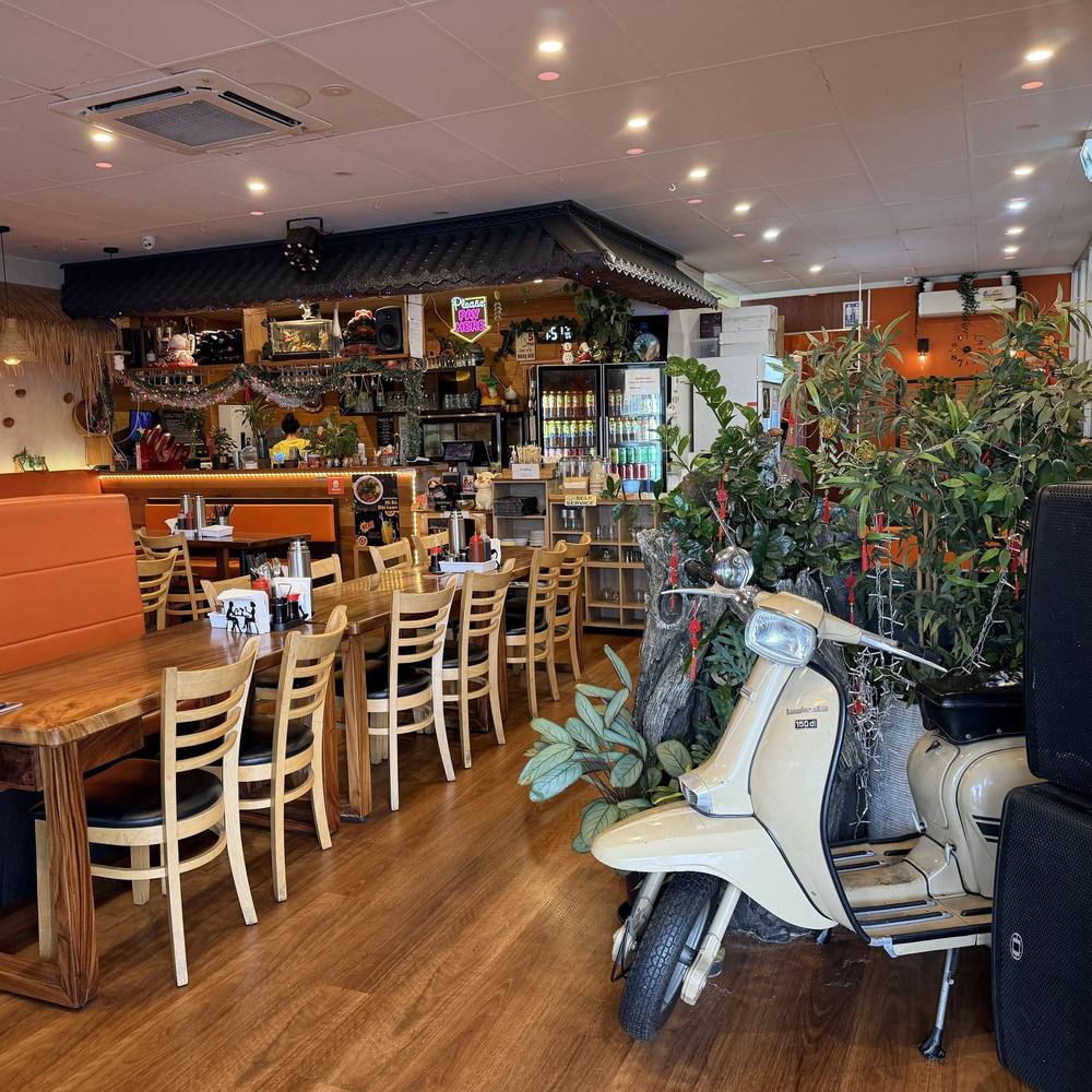 Inside Cô Năm on Athol Road: warm timber room, orange booths, plants and neon