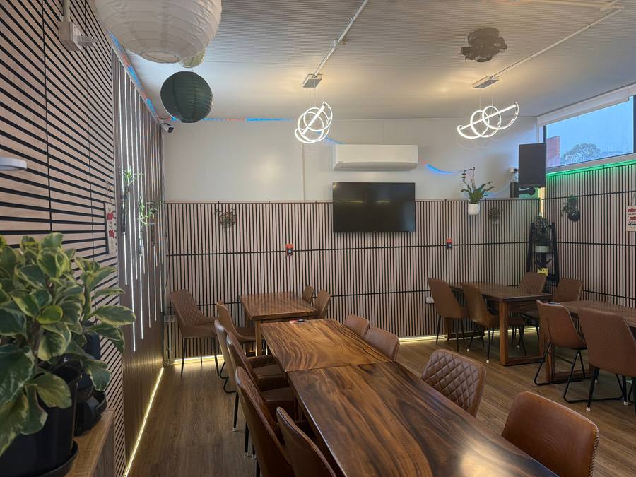 The VIP room at Windsor Avenue: one long timber table set with leather chairs against a backlit slat wall
