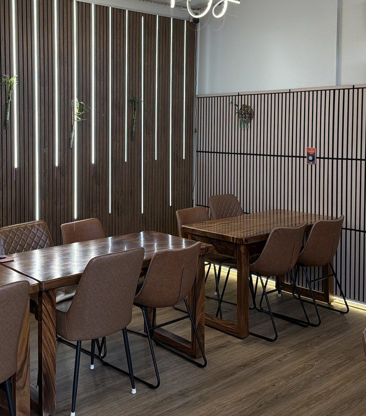 Brown leather chairs along timber tables in the private room, against a backlit slat wall